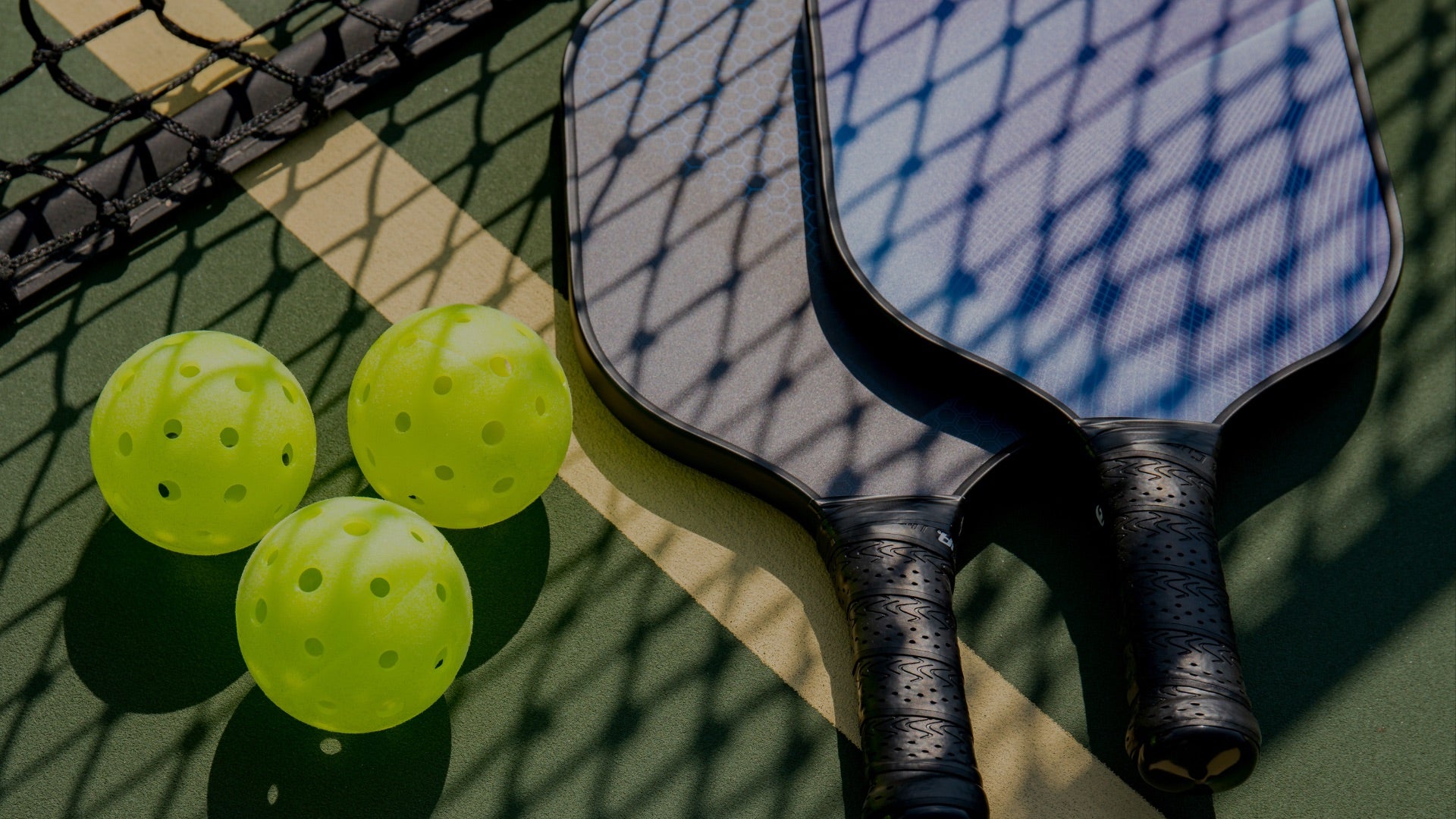 Pickleball paddle and balls on a green court - MatchSet Racquet Sports